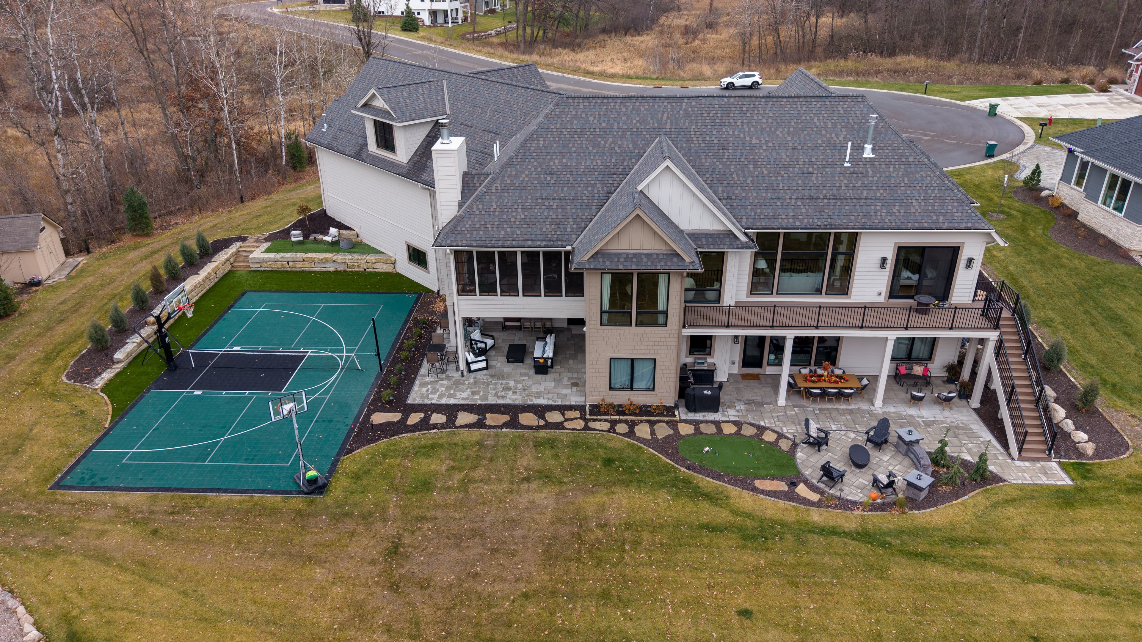 Modern home with basketball court and landscaped yard in a serene setting.