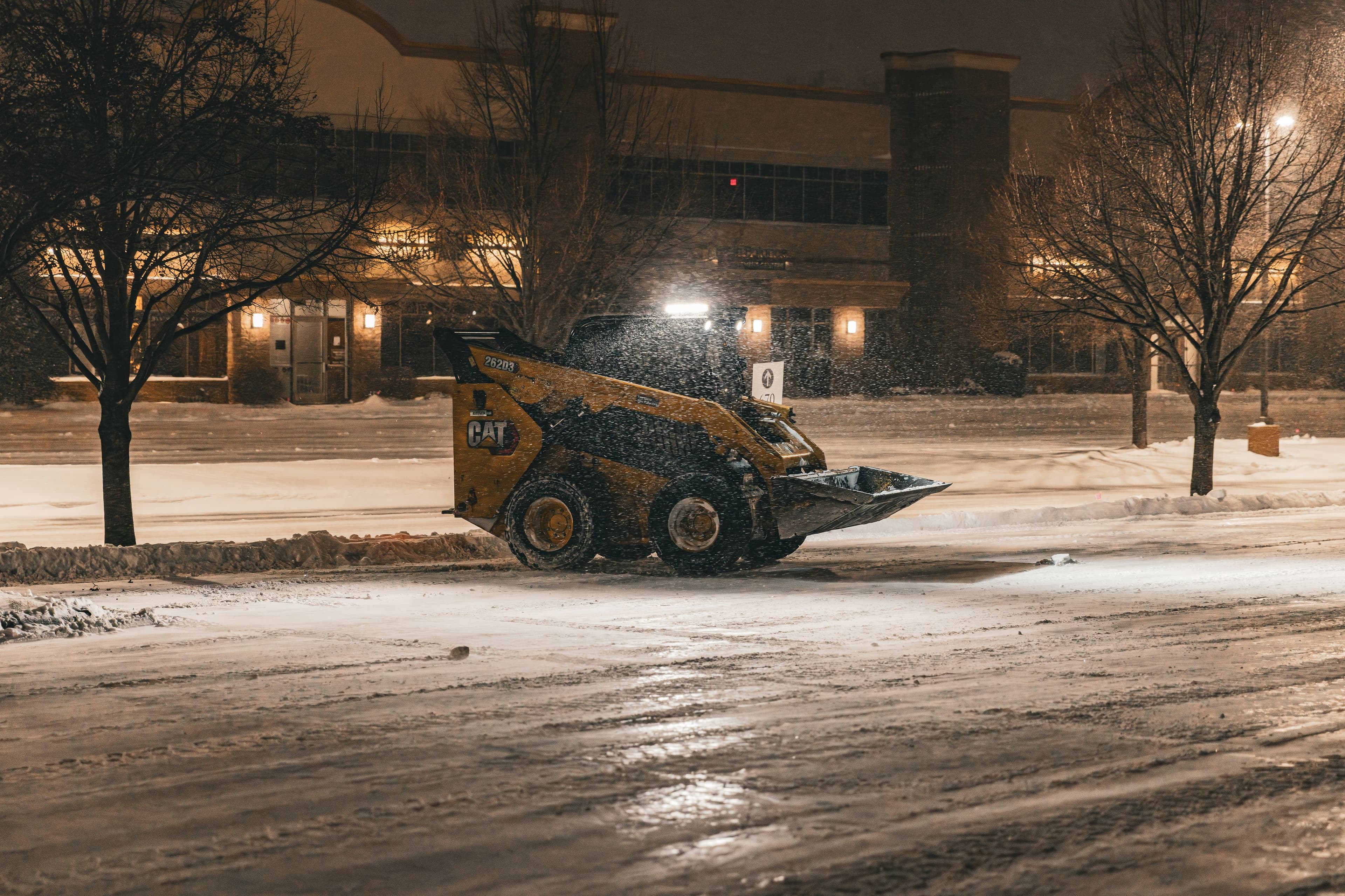 Snow removal machine clearing streets during a winter night snowstorm.