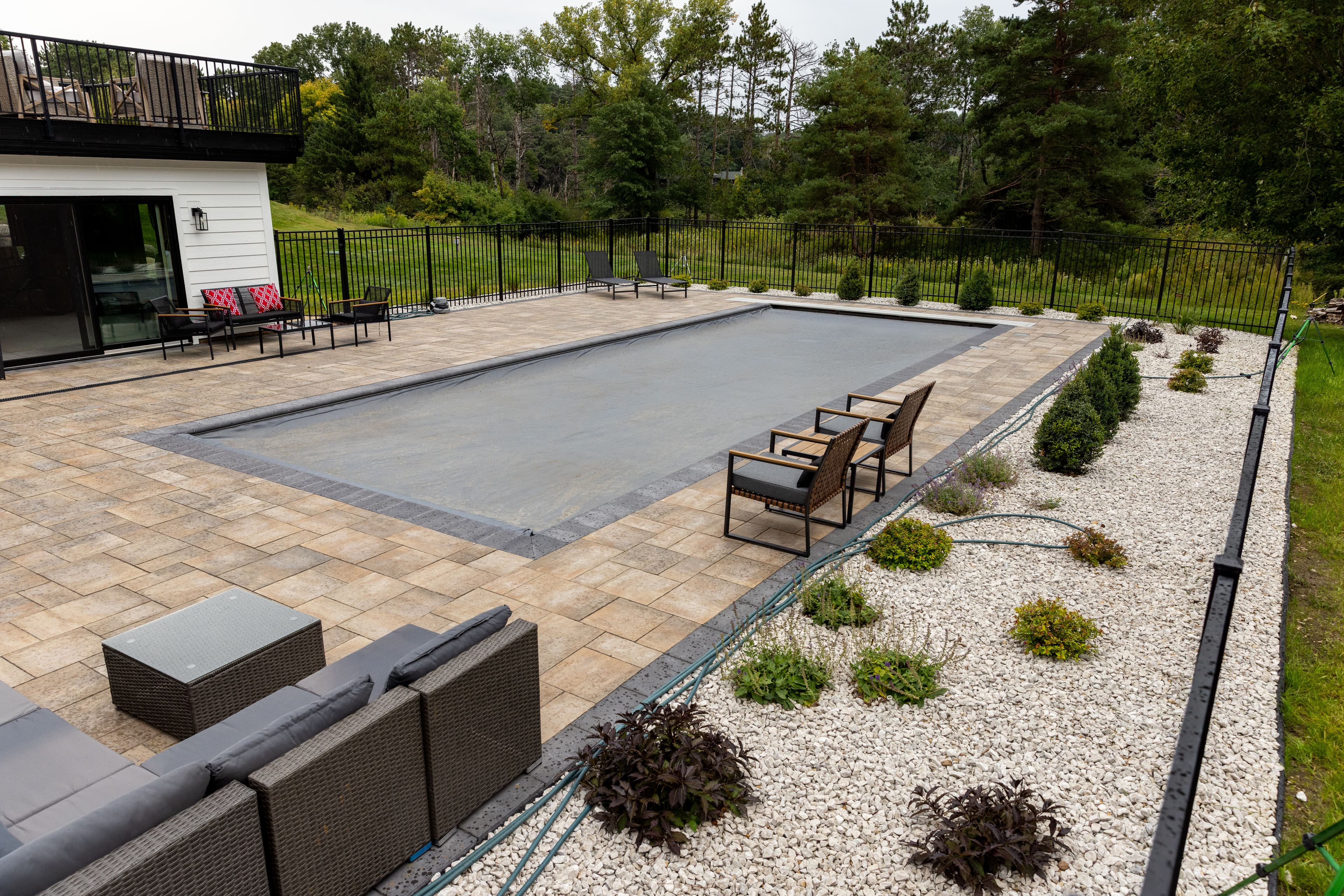 Modern backyard with a rectangular pool, patio seating, and landscaped garden.