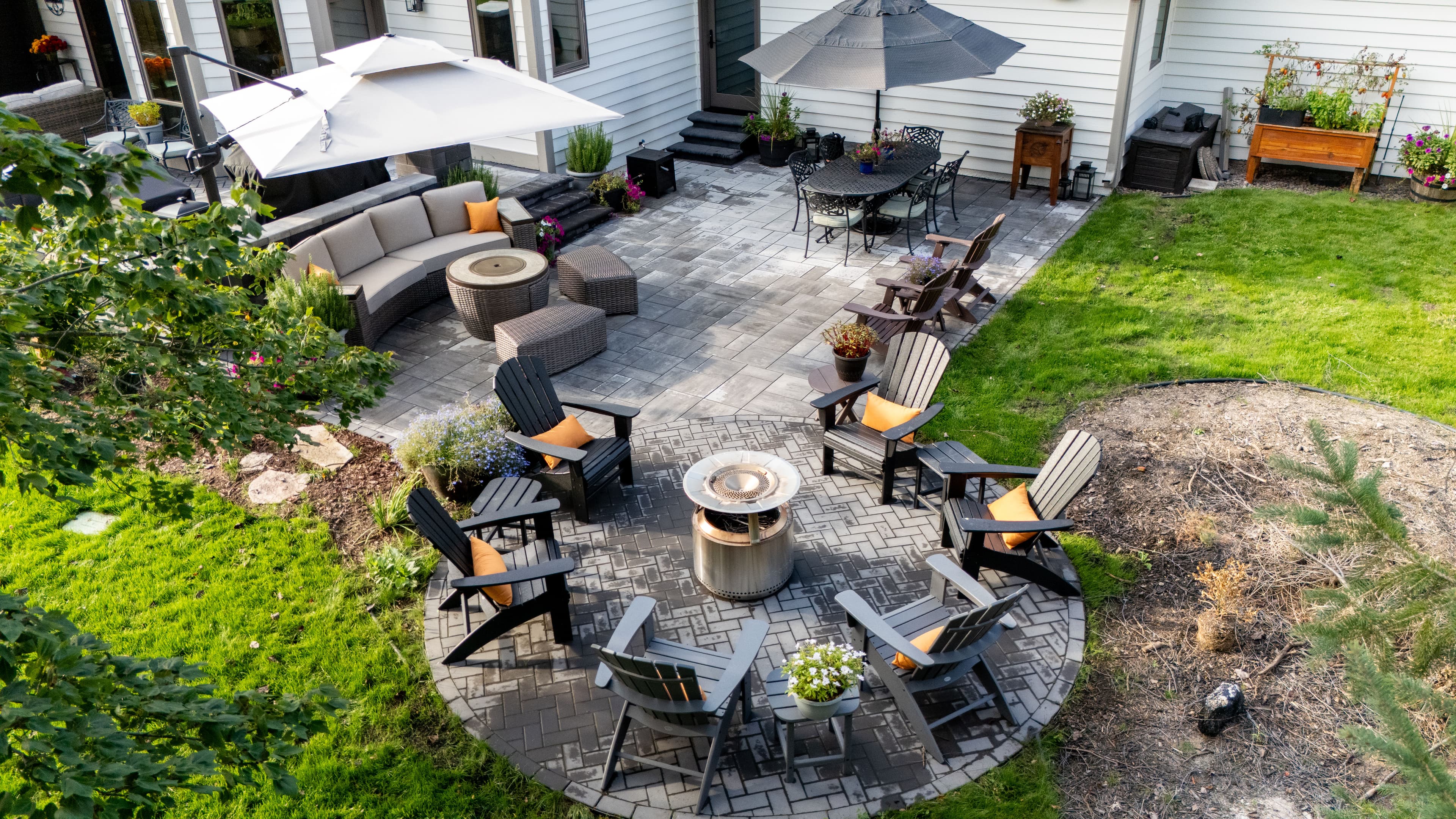 Aerial view of a landscaped backyard with seating area and fire pit surrounded by plants.