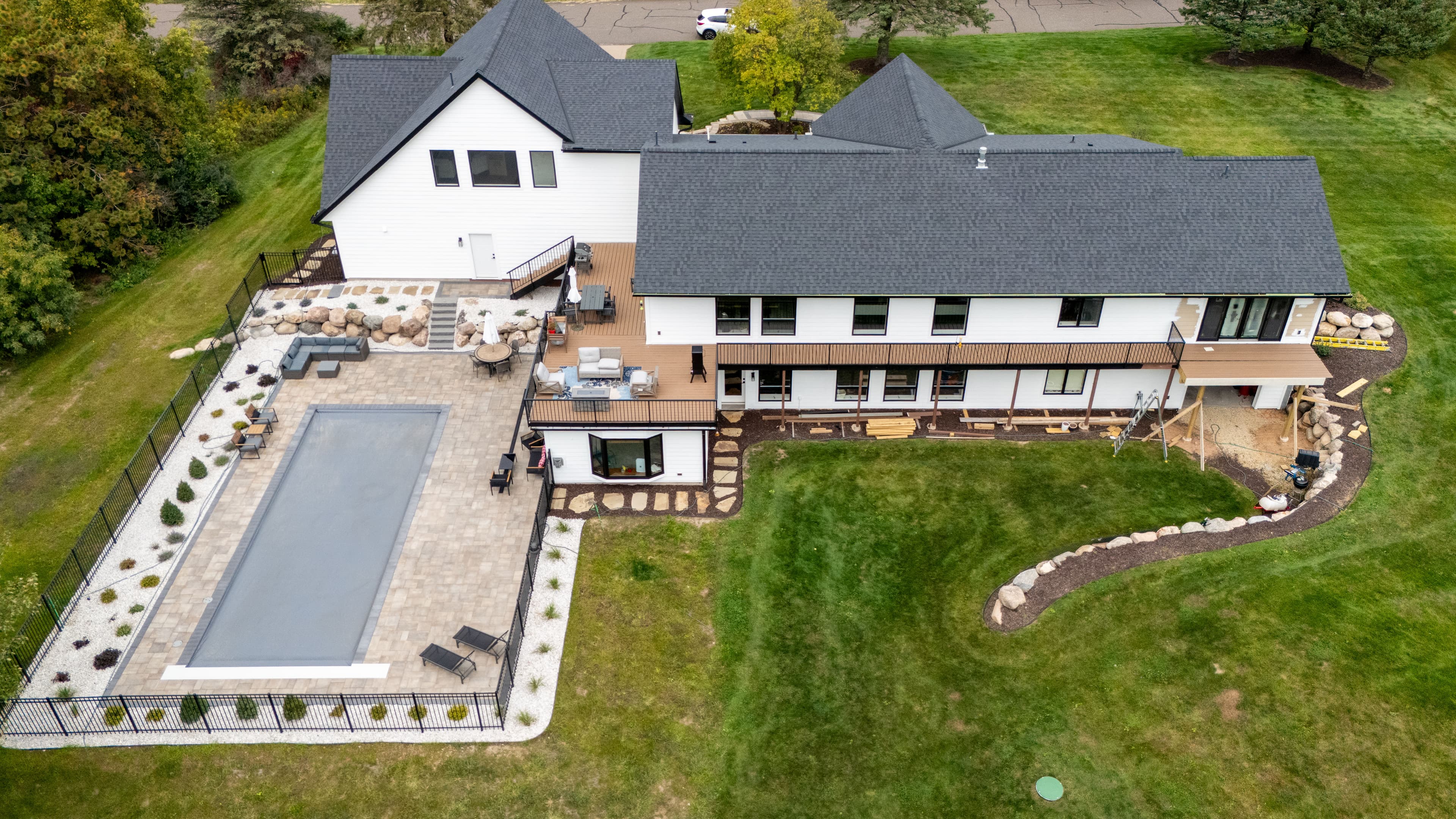 Aerial view of a modern home with a patio, pool, and landscaped yard.