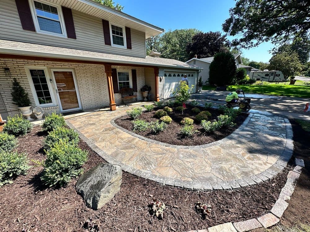 Landscaped front yard with stone walkway, colorful plants, and well-maintained lawn.