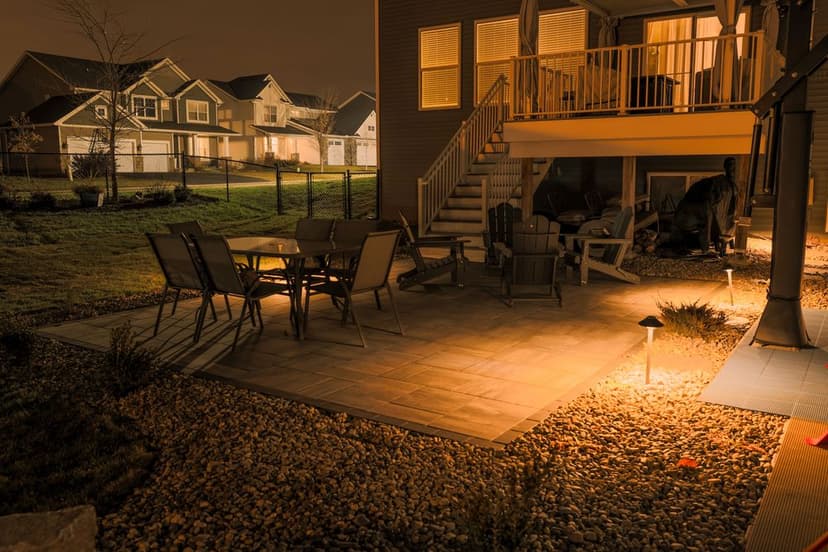 Cozy backyard patio at night with modern seating and illuminated stone pathway.