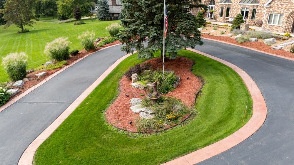Aerial view of a landscaped circular driveway with flagpole and garden features.