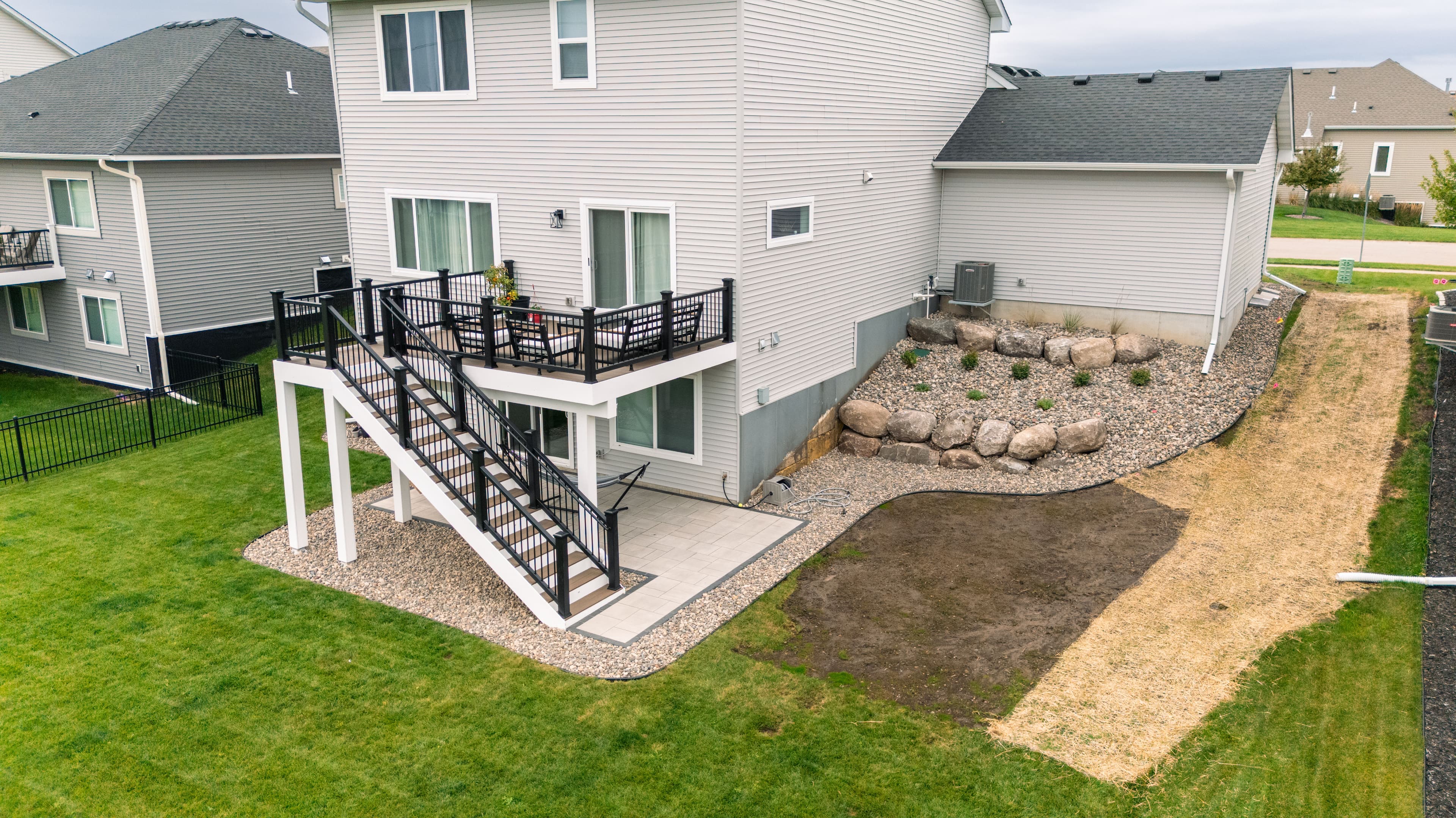 Aerial view of a modern home with a landscaped yard, patio, and stairs.