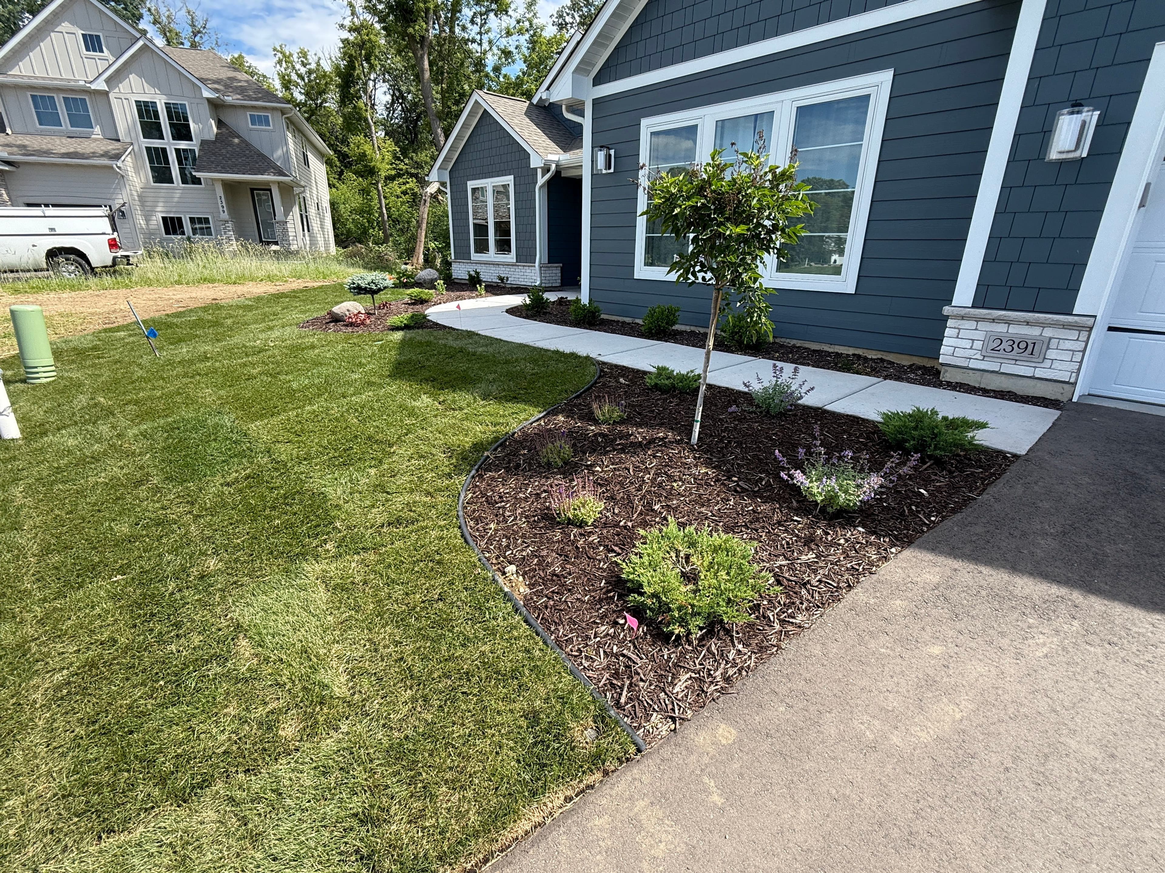 Well-maintained front yard with lush grass and landscaped flower beds near a contemporary home.