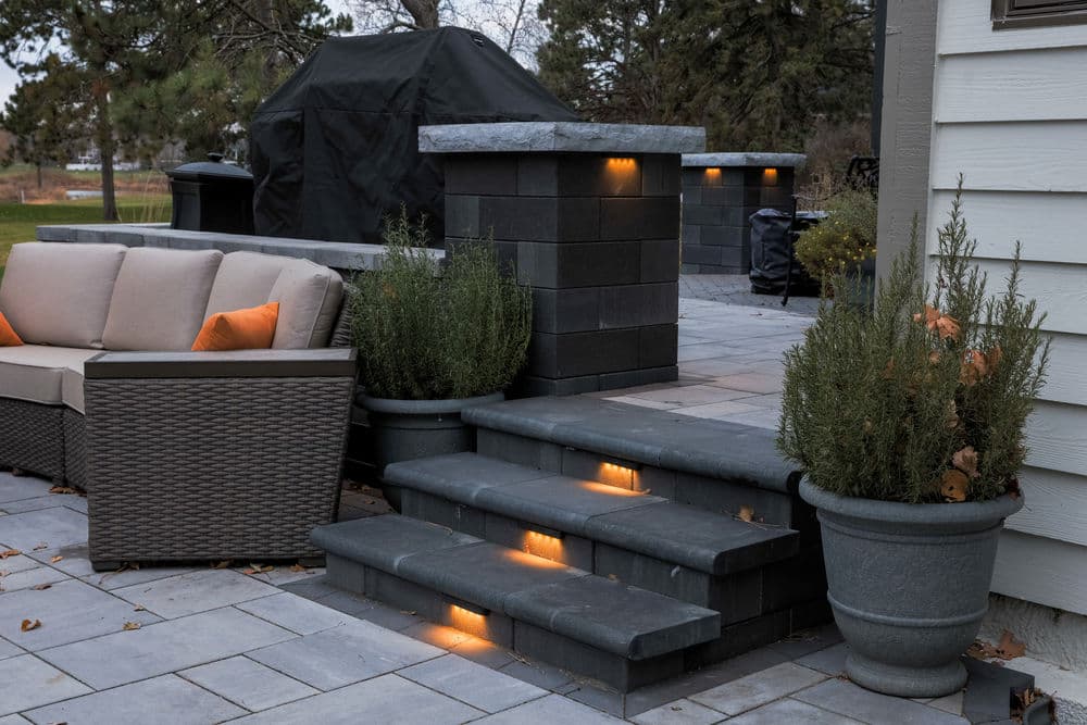 Cozy outdoor patio with stairs, seating, and landscaping featuring modern lighting elements.